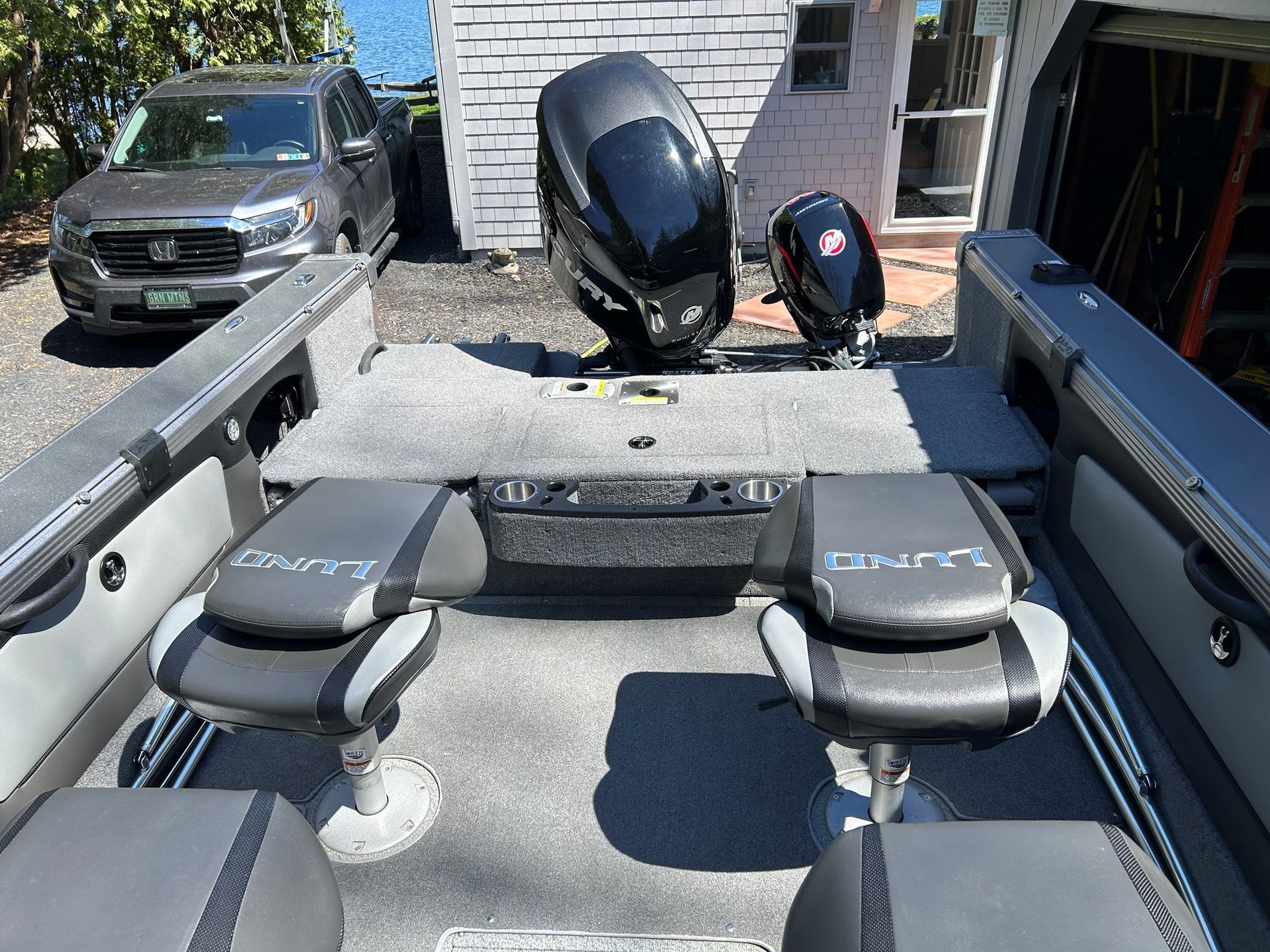 Boat interior with two gray/black seats, two outboard motors, and a gray deck.