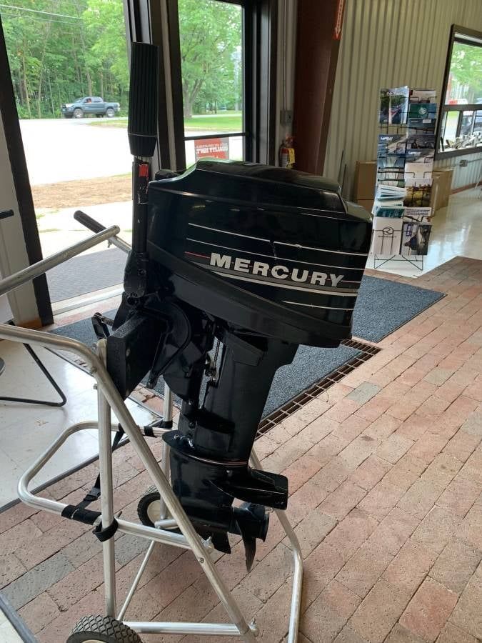 Black Mercury outboard motor on a silver stand, inside a building.
