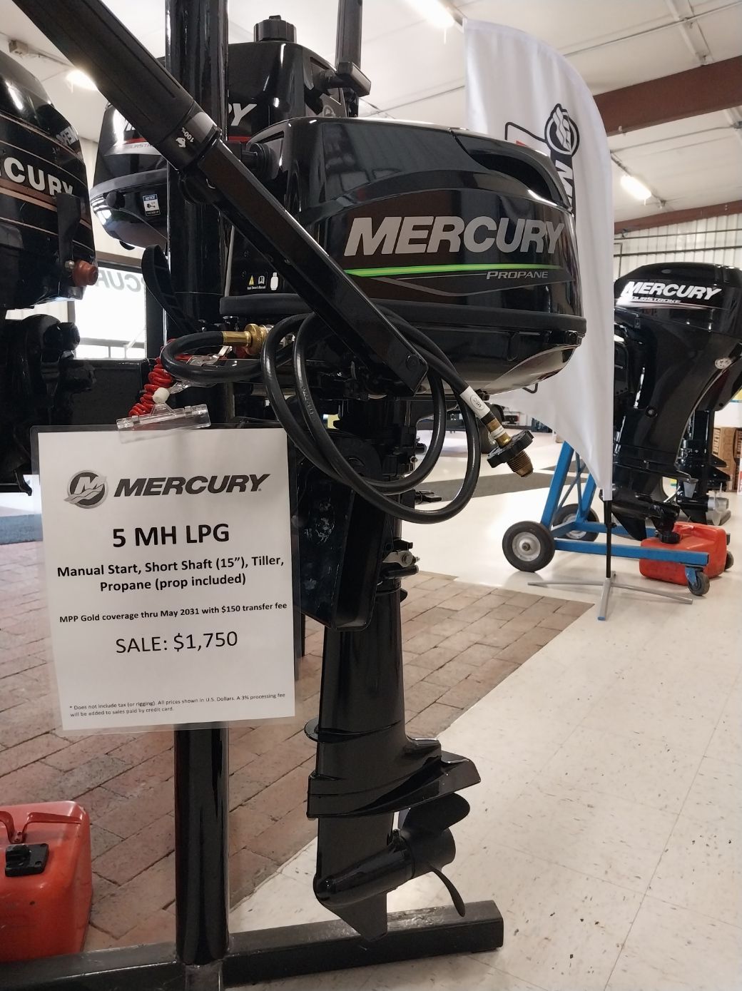 Black Mercury 5 MM LPG outboard motor on display with a price tag.