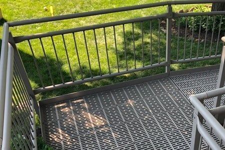 Metal platform with railing overlooking grassy area.