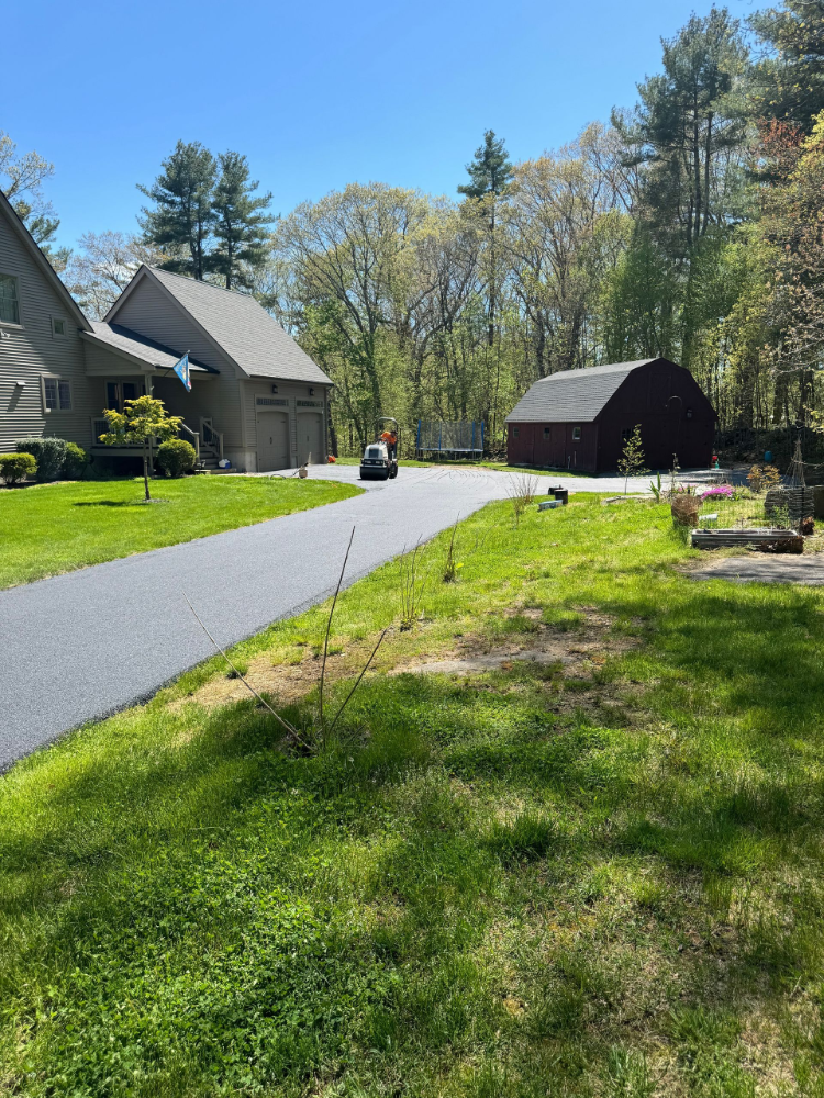 A car is driving down a road next to a house