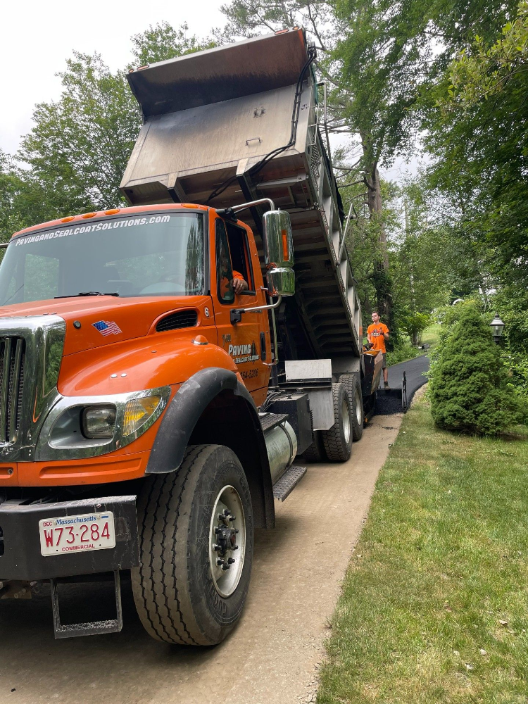 An orange dump truck is parked on the side of a road.