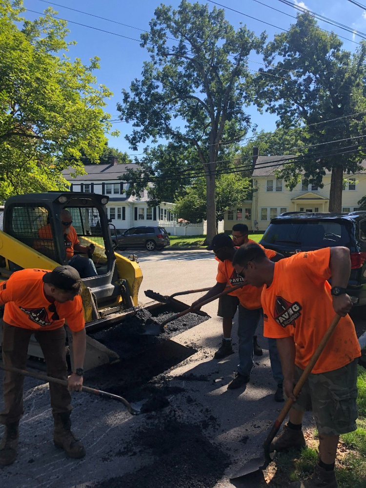 A group of men wearing orange shirts are working on a sidewalk