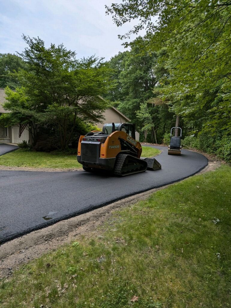 A bulldozer is driving down a road next to a house.