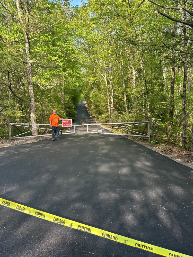 A man in an orange shirt is standing on the side of a road.