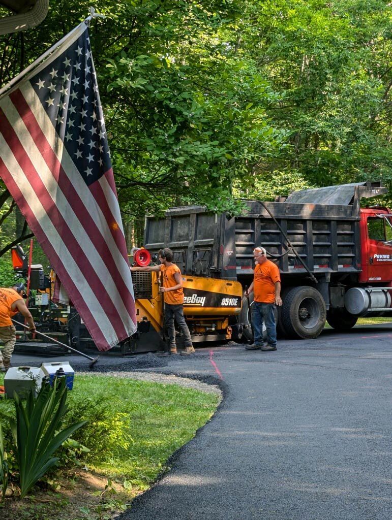 An american flag is flying in front of a dump truck