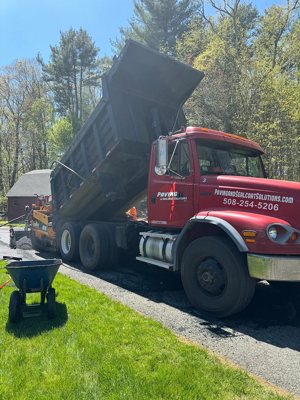 A red dump truck is parked on the side of a road.