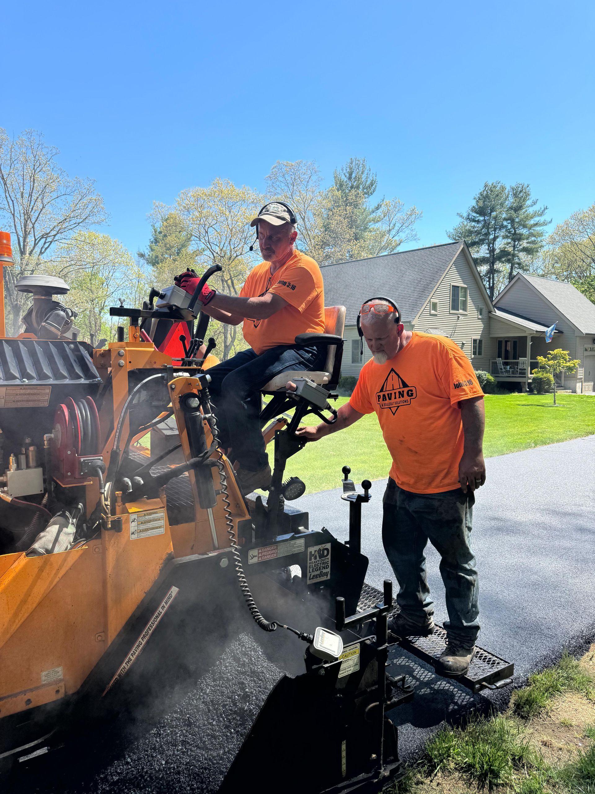Two men are working on a road with a machine.