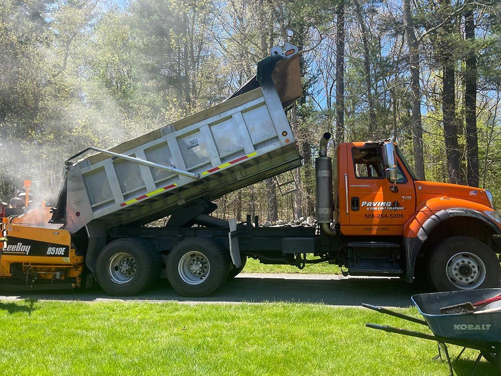 A dump truck is being loaded with concrete in a driveway.