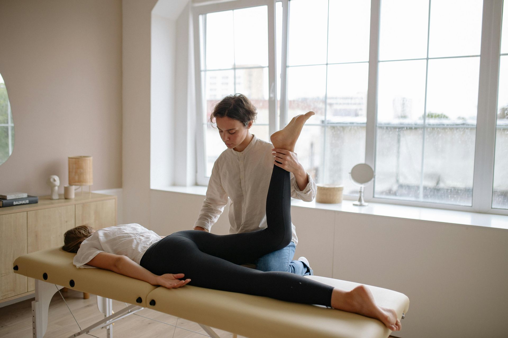 Physical therapist stretching a patient’s leg on a treatment table in a bright clinic room