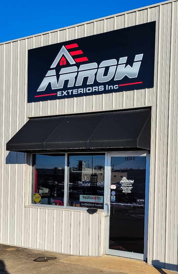 A building with a black awning and a sign that says arrow exteriors