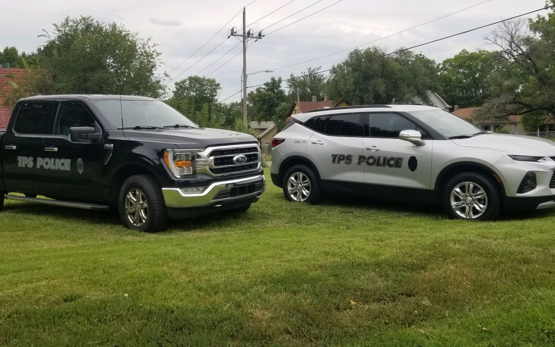 Two police cars are parked next to each other in a grassy field.