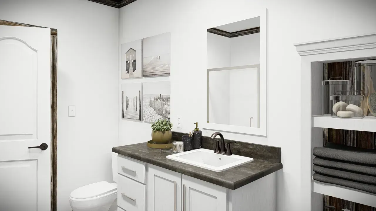 White bathroom with a vanity, sink, and mirror. Artwork hangs on the wall, and a towel closet is visible.