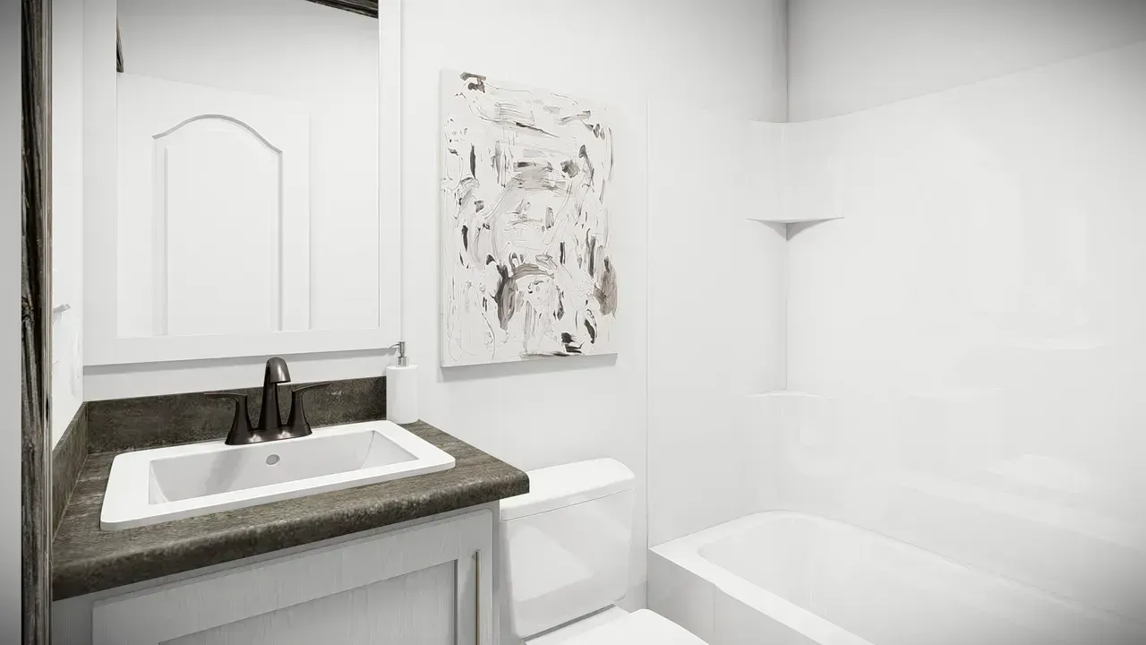 Small, bright white bathroom with a vanity, toilet, and bathtub. A piece of art hangs on the wall.