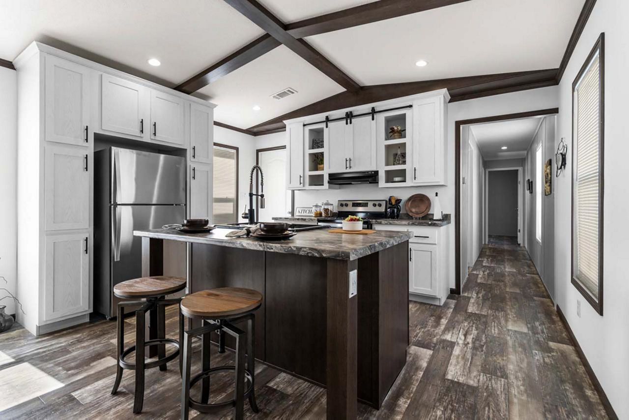 Modern kitchen with dark wood island, stainless steel appliances, and white cabinets. The kitchen has wood flooring and is in a home.