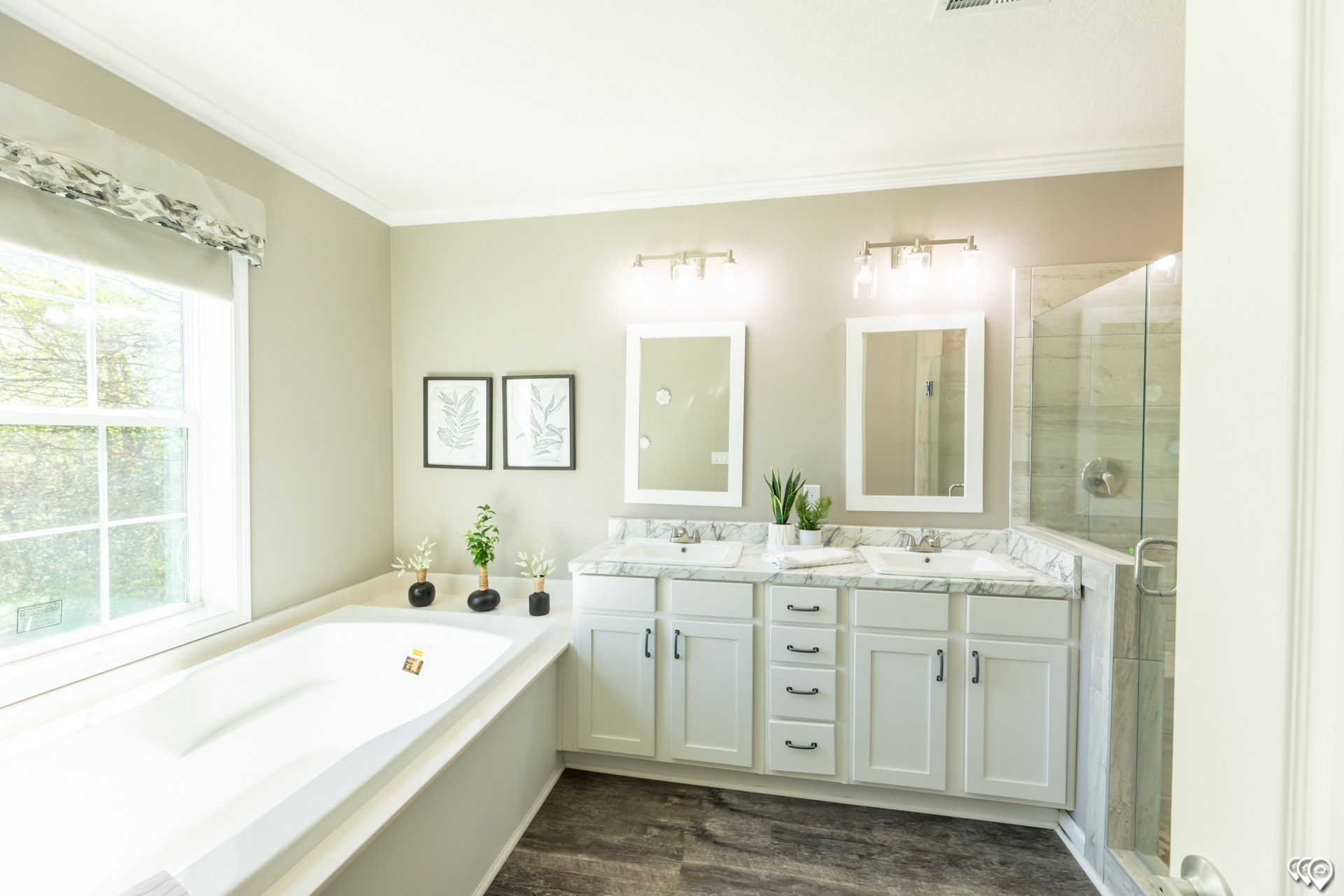 A bathroom with a tub, sinks, mirrors, and a window.
