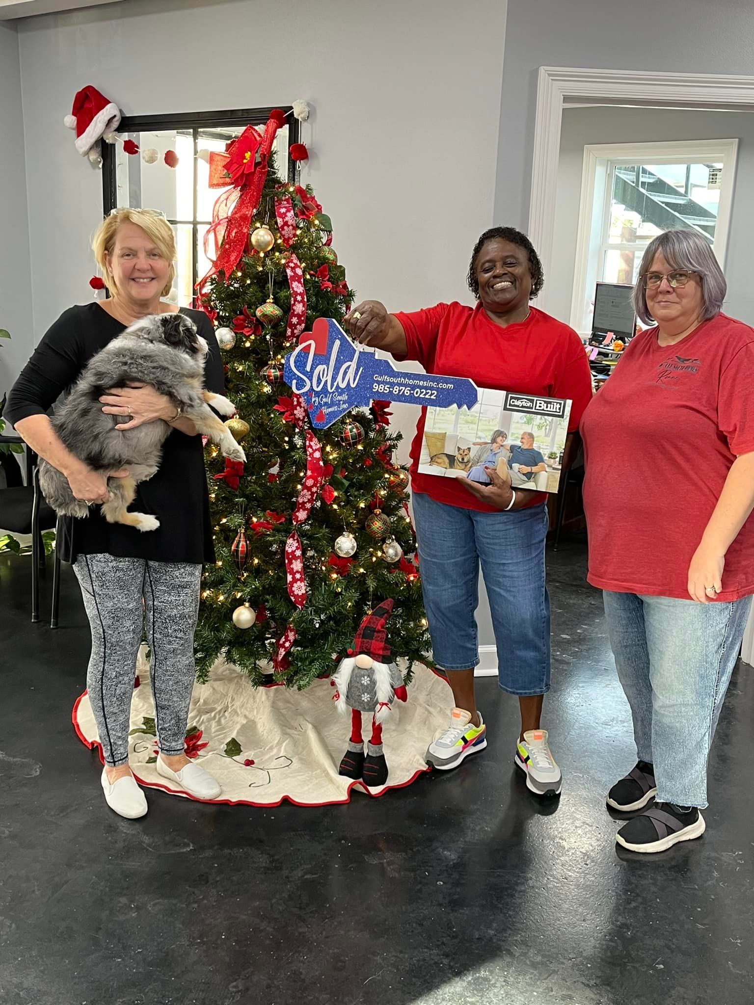 Three women are standing in front of a christmas tree