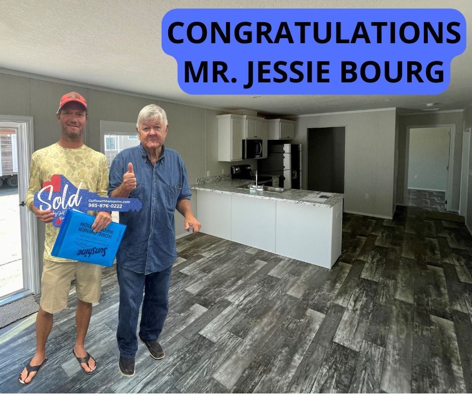 Two men are standing in a kitchen holding a sold sign