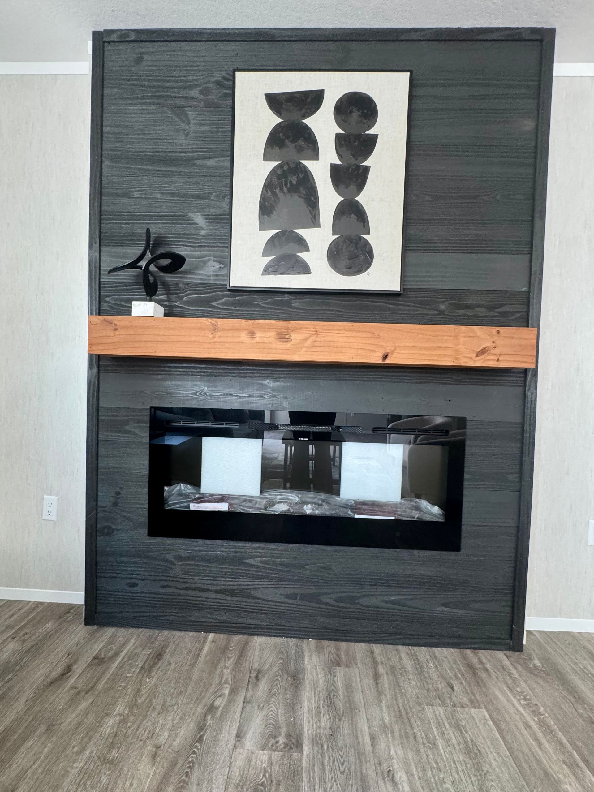 A fireplace with a wooden mantle and a painting on the wall above it.