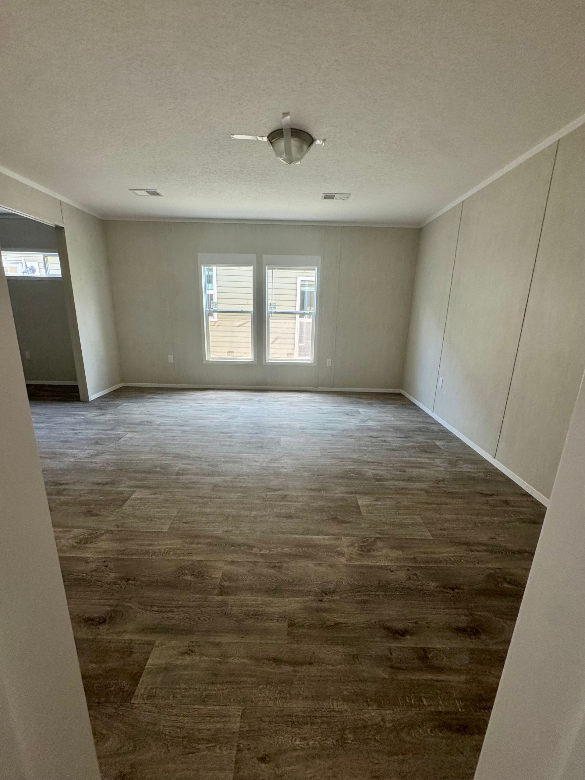 An empty living room with hardwood floors and a ceiling fan.