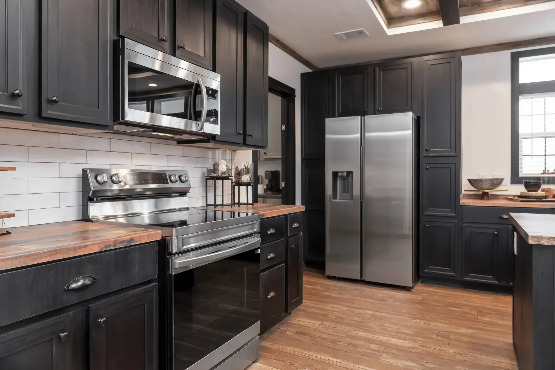 A kitchen with black cabinets and stainless steel appliances.