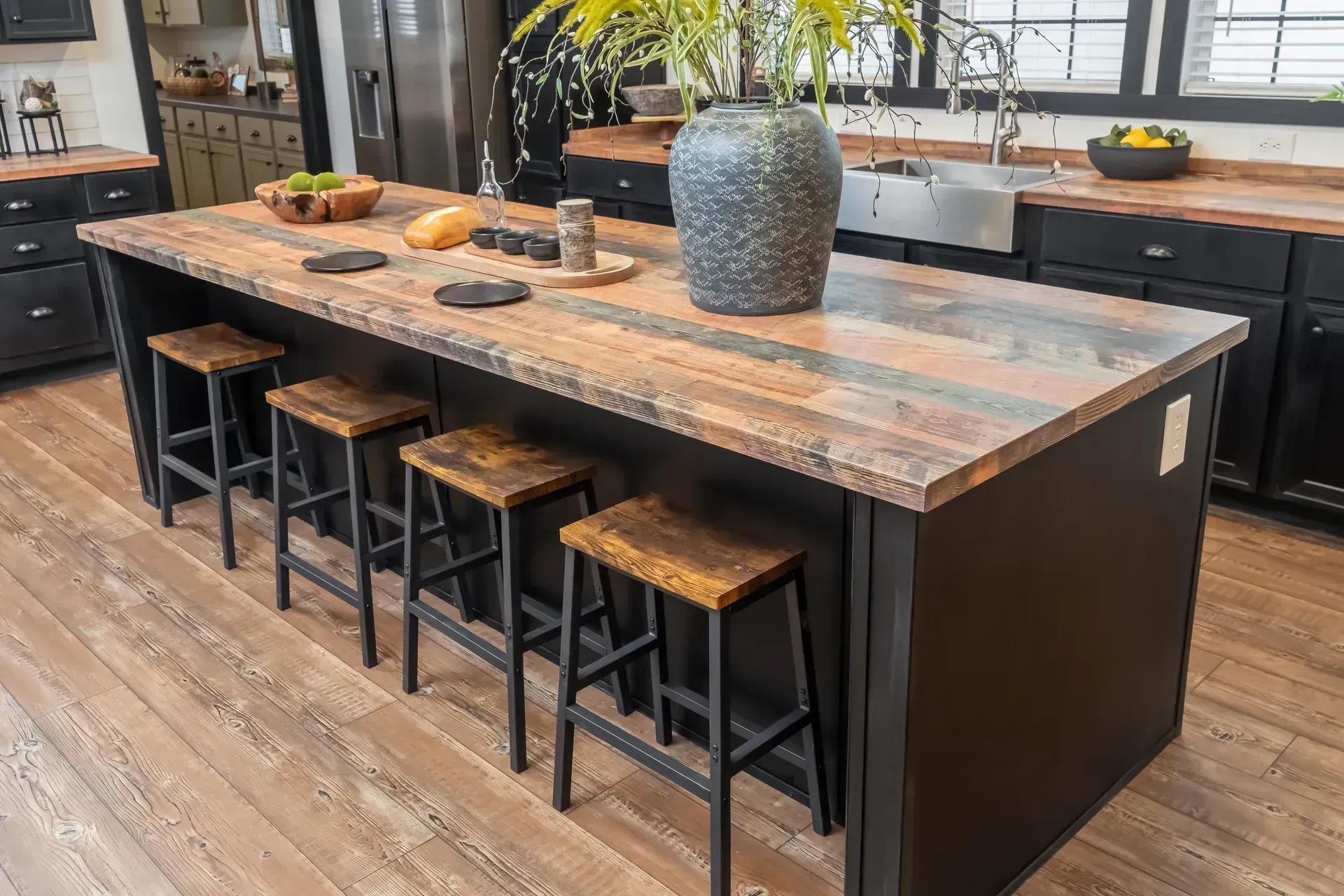 There is a large island in the middle of the kitchen with stools.
