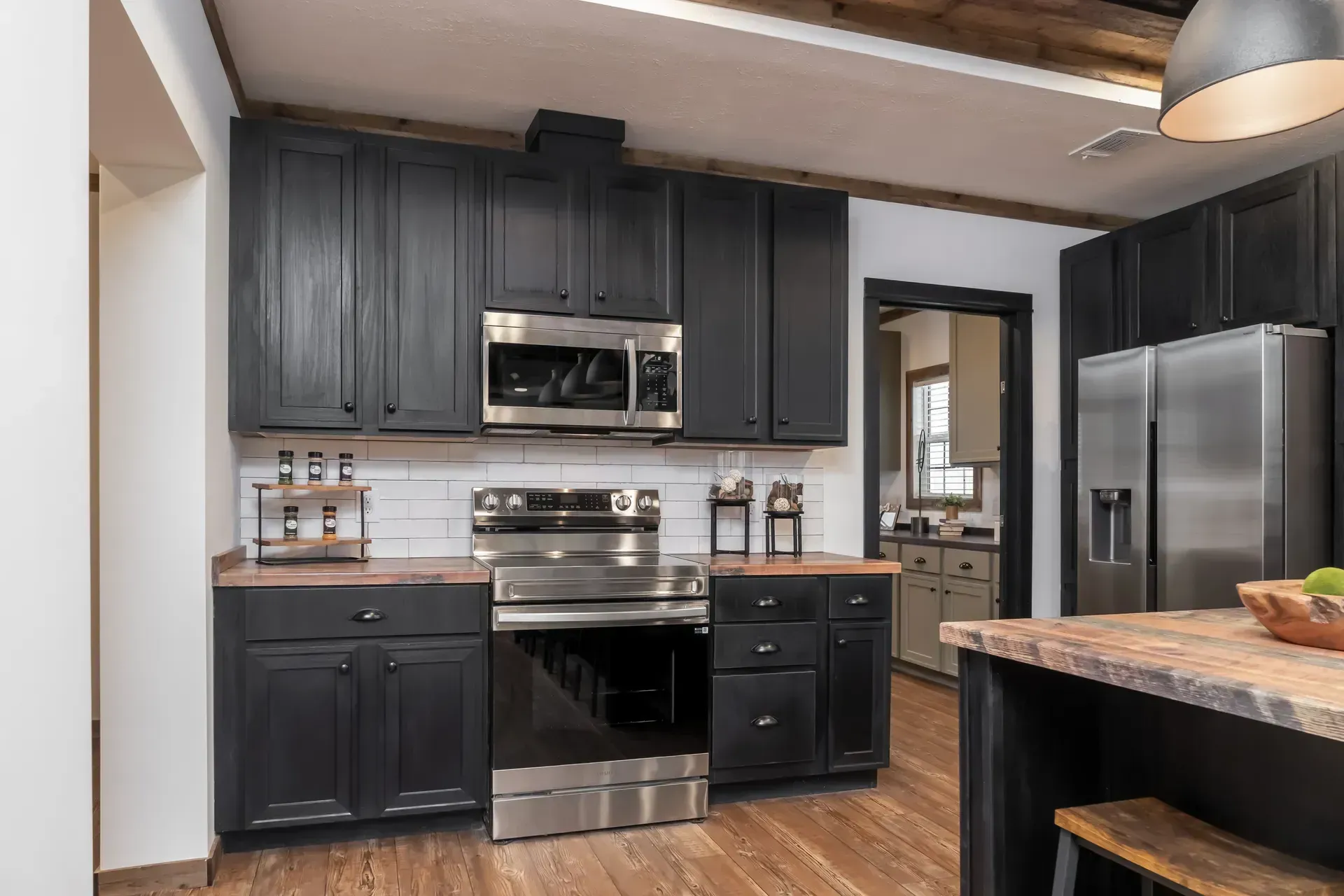 A kitchen with black cabinets and stainless steel appliances.