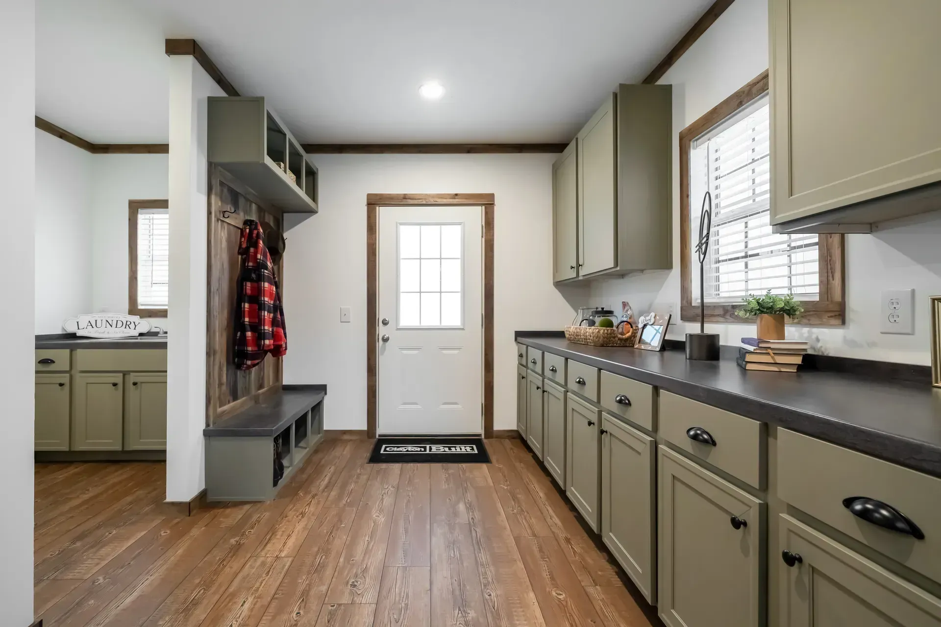 A kitchen with green cabinets and wooden floors and a white door.