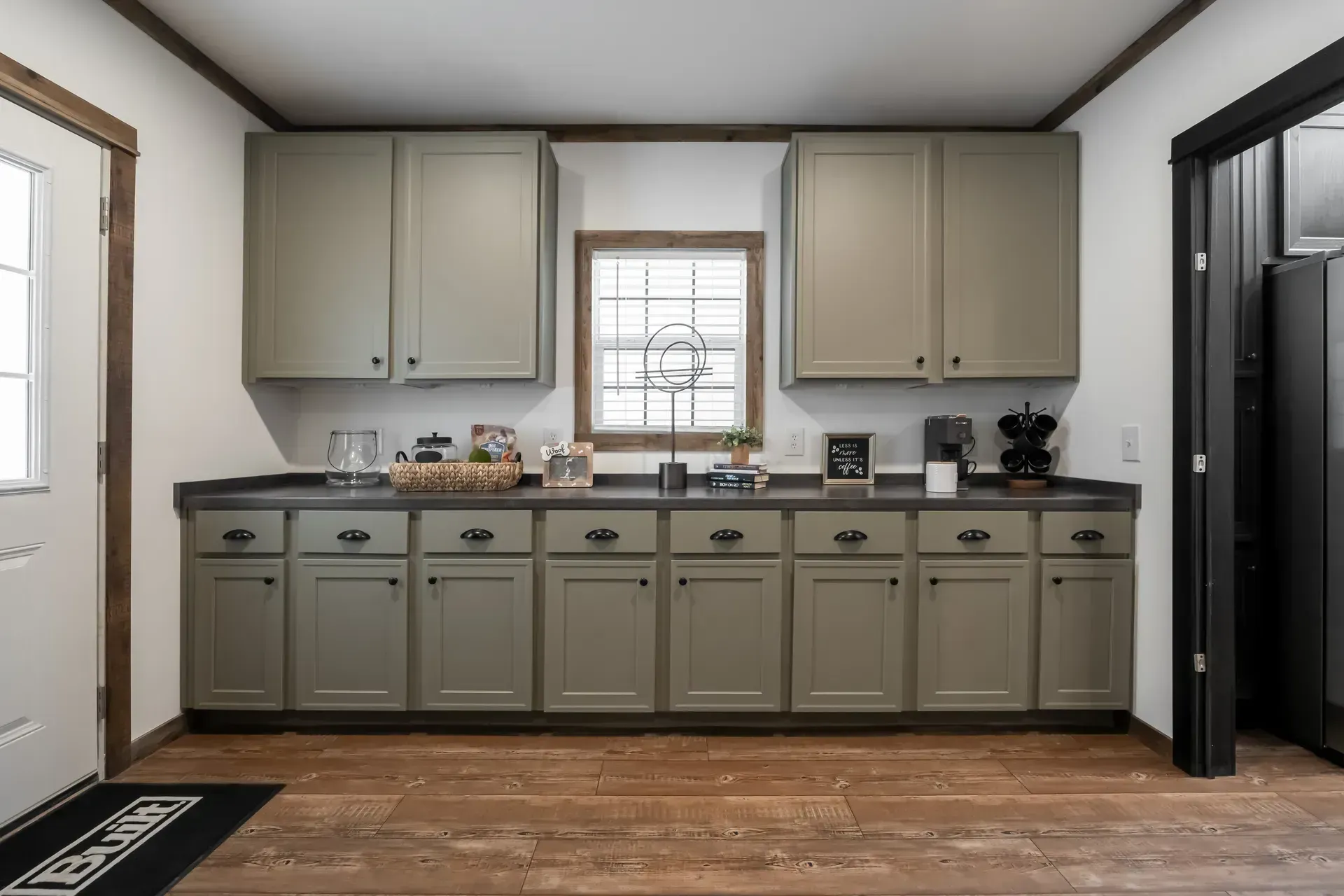 A kitchen with a lot of cabinets and drawers and a window.