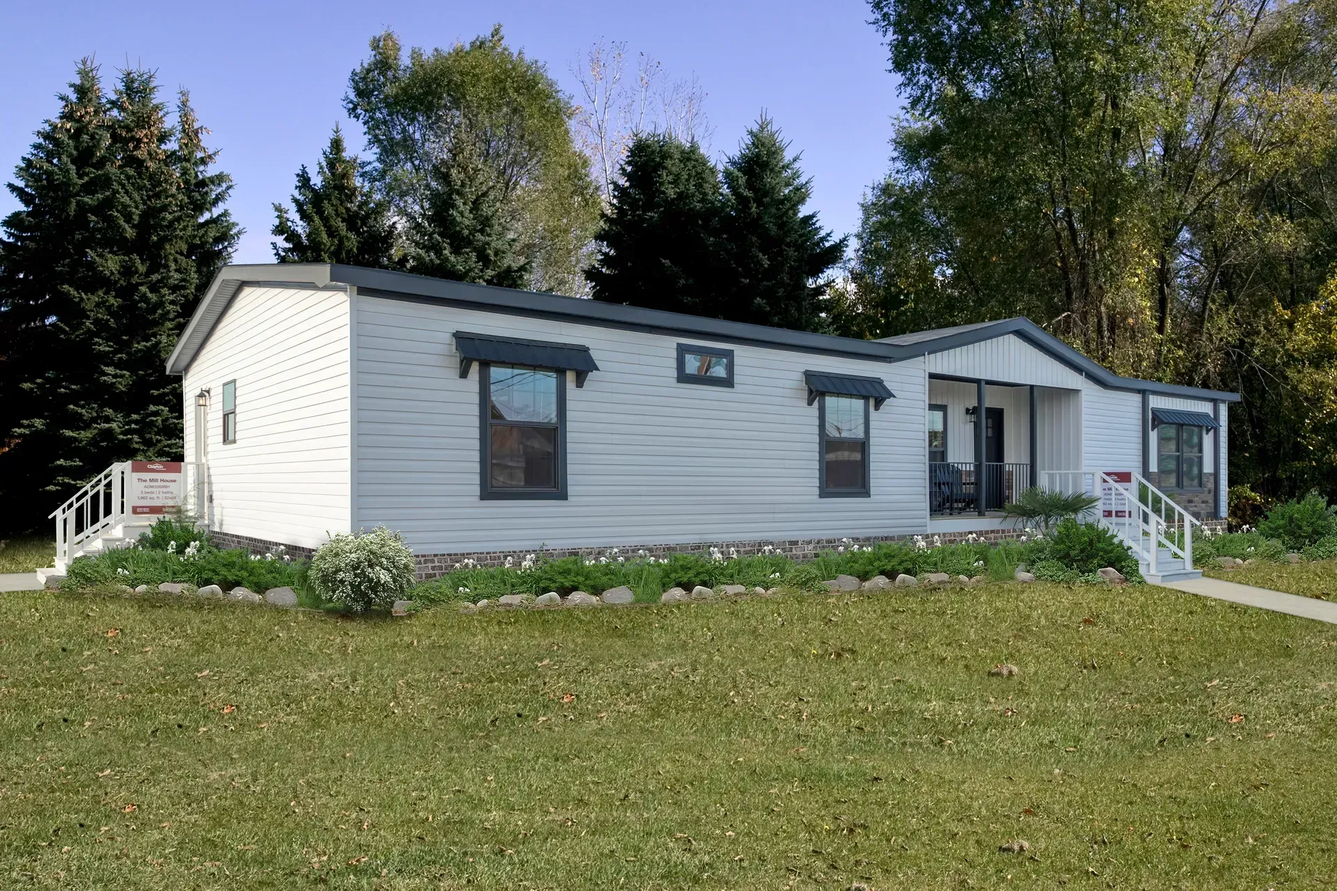 A white mobile home is sitting on top of a lush green field.