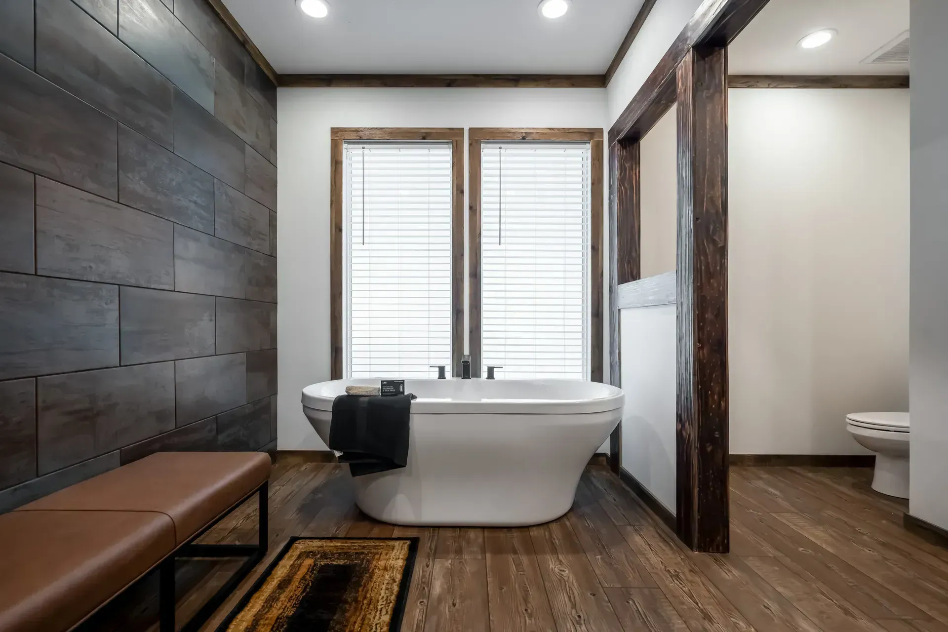A bathroom with a tub, toilet, and bench.
