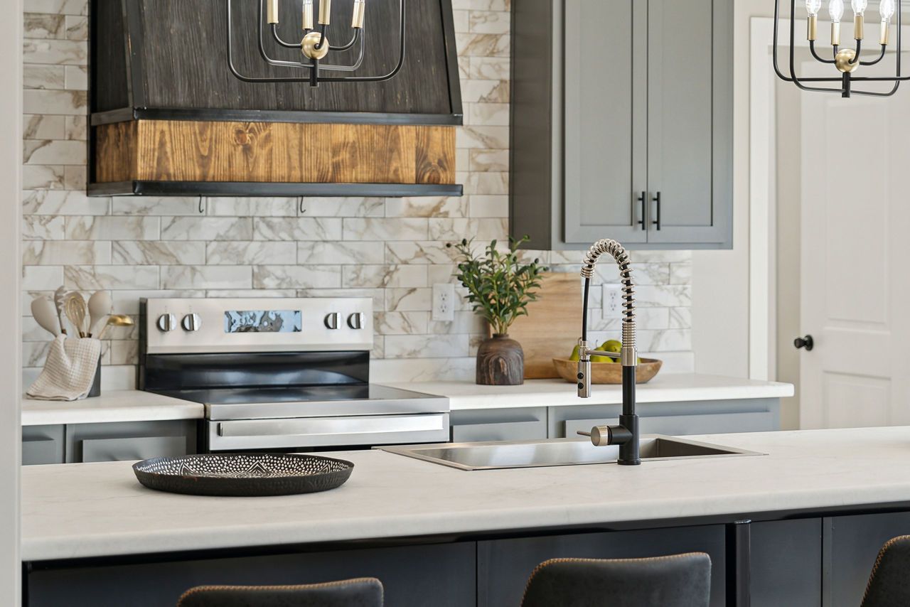 Kitchen with gray cabinets, stainless steel appliances, and a wood range hood.