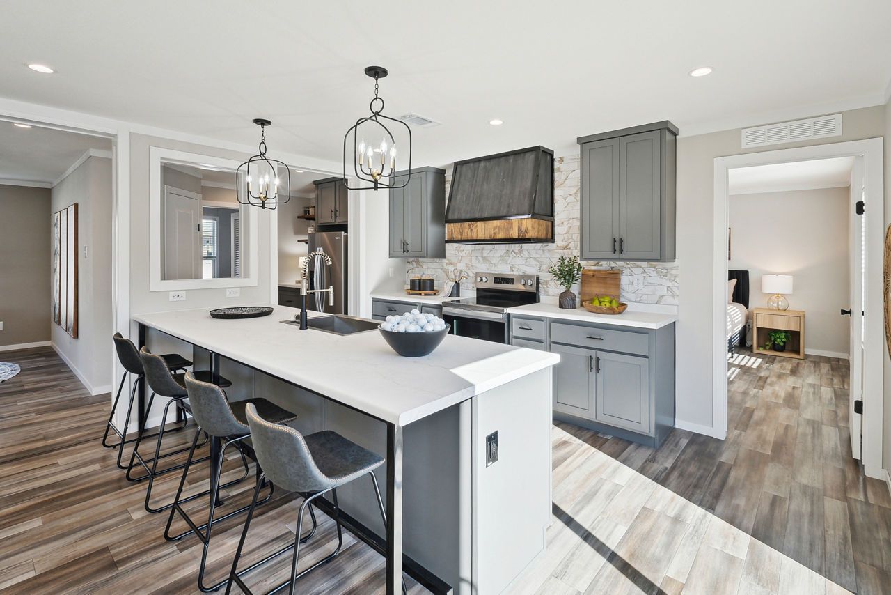 Modern kitchen with gray cabinets, white countertops, and a breakfast bar.