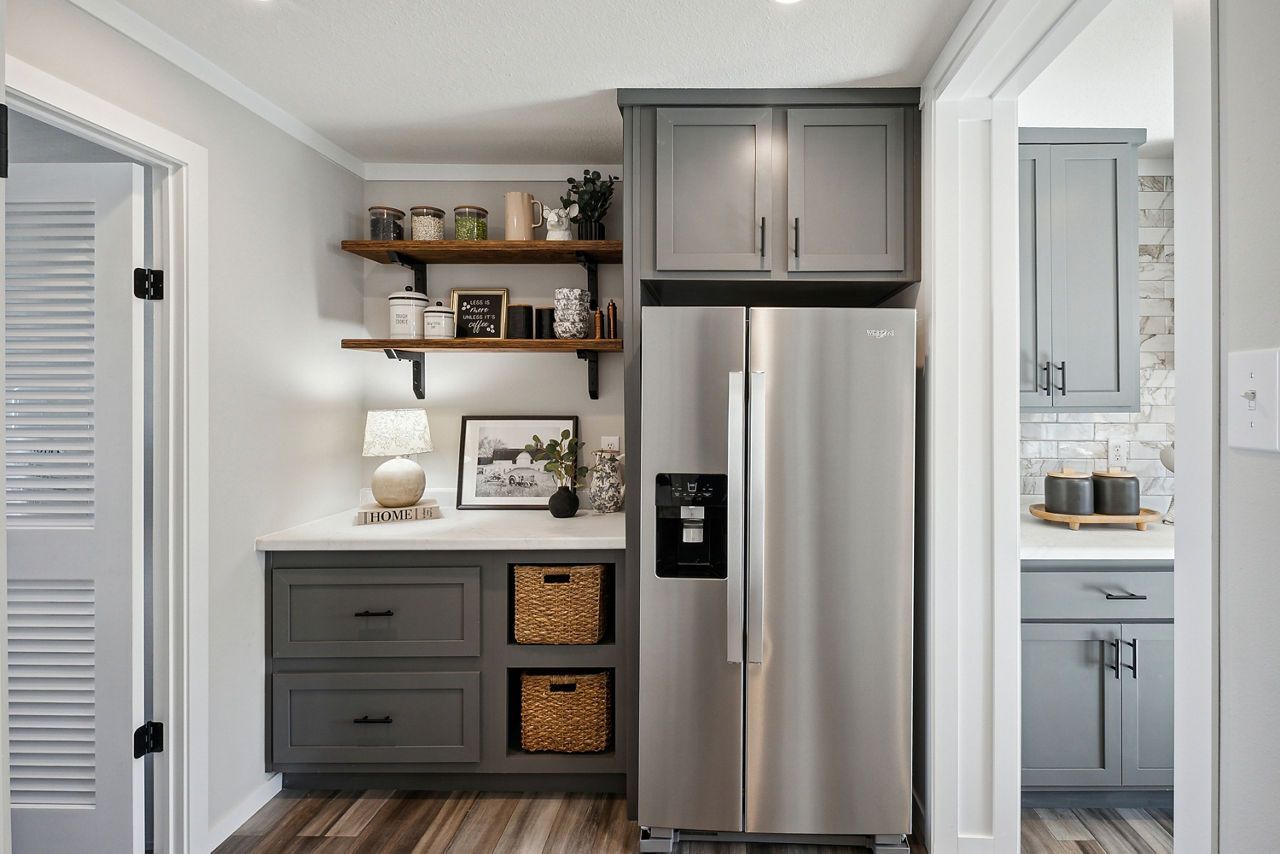 Kitchen with grey cabinets, refrigerator, open shelves, and wicker baskets.