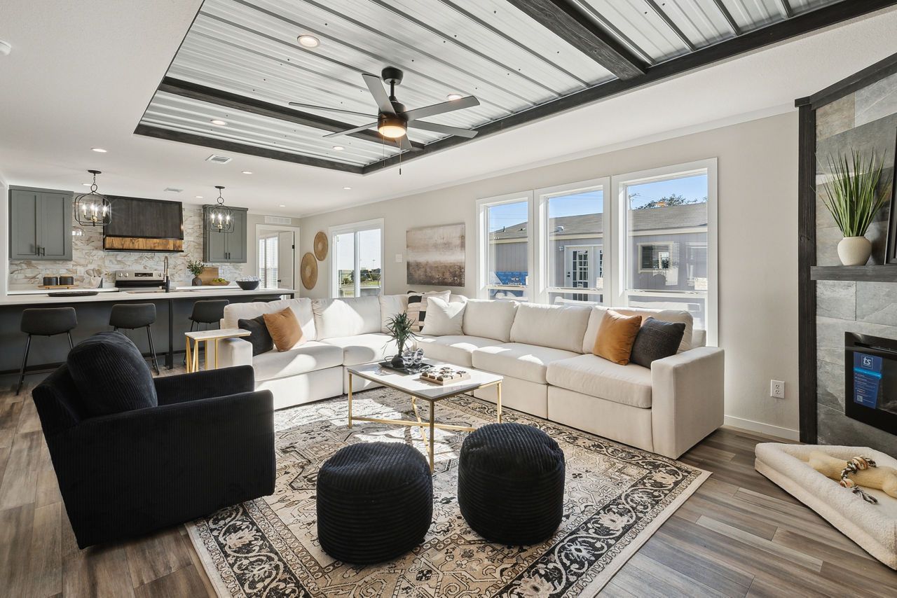 Open concept living space with kitchen, light colored sofa, fireplace, and patterned rug.
