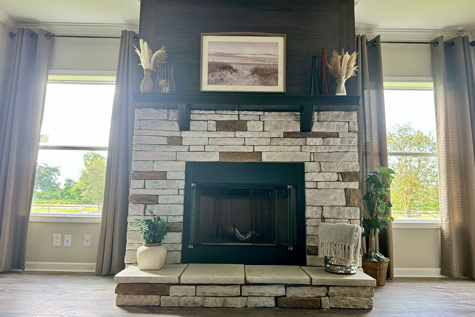 A living room with a fireplace and two windows.