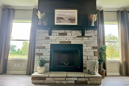 A living room with a fireplace and two windows.