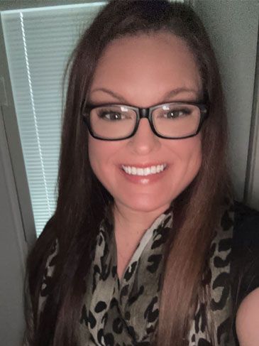 A woman wearing glasses and a scarf is smiling for the camera.