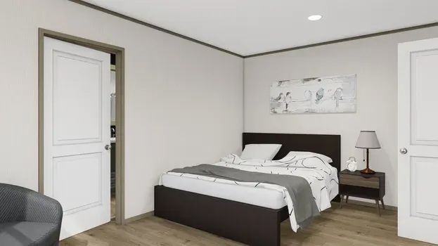 Bedroom with bed, nightstand, closet, and a chair. White walls, brown bed frame, and artwork.