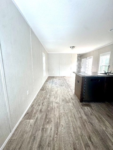 Interior view of a room with gray wood-look flooring and white panel walls. A dark island is on the right.