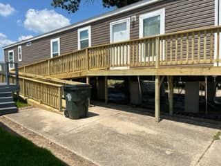 A mobile home with a wooden deck and ramp.