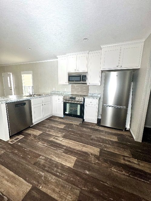Kitchen with white cabinets, stainless steel appliances, and dark wood-look flooring.