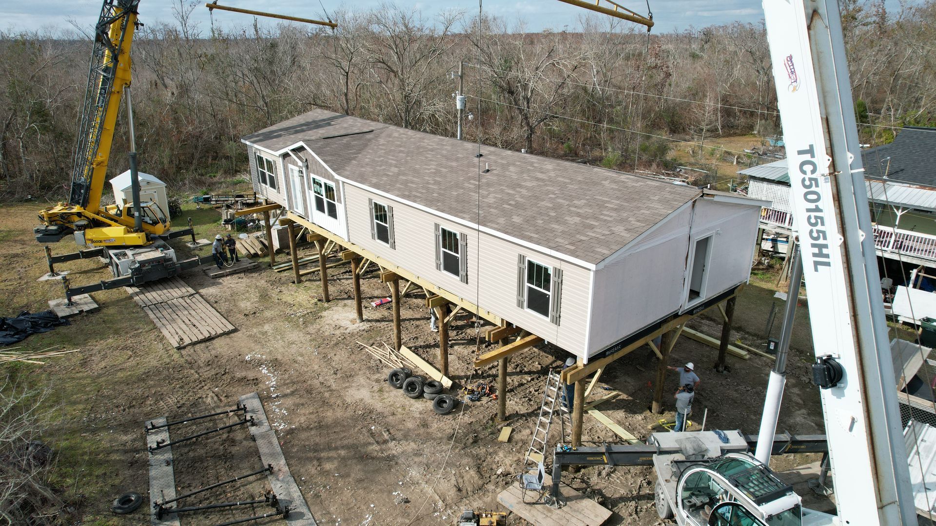 An aerial view of a mobile home being built on stilts.