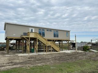 A house on stilts with a wooden deck and stairs.