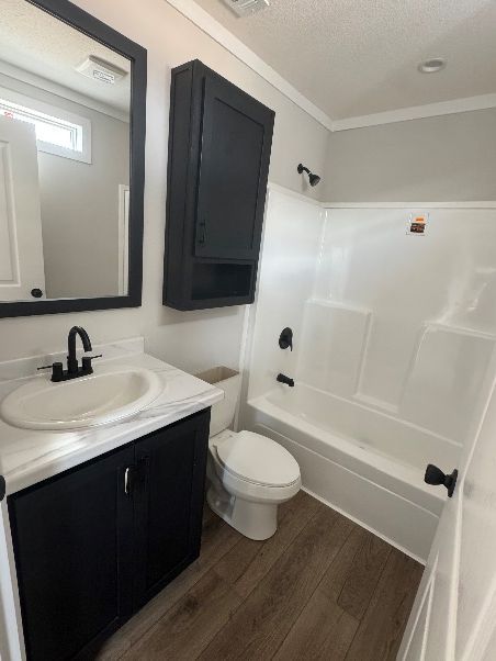Bathroom with white fixtures, black vanity and storage cabinet, and wood-look flooring.