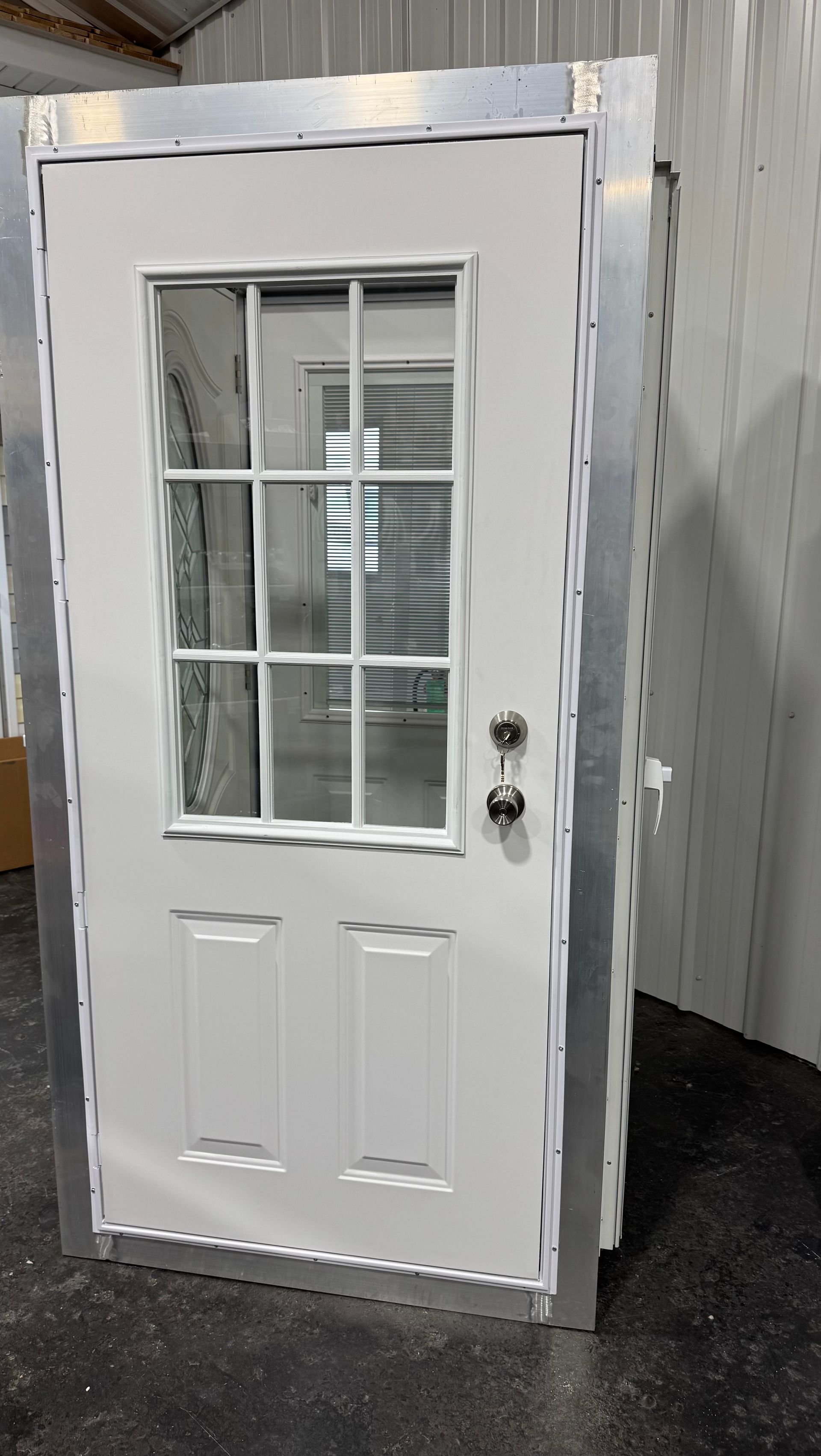 A white door with a window is sitting in a warehouse.