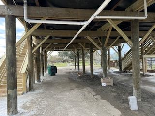 The underside of a wooden structure with stairs and pipes.