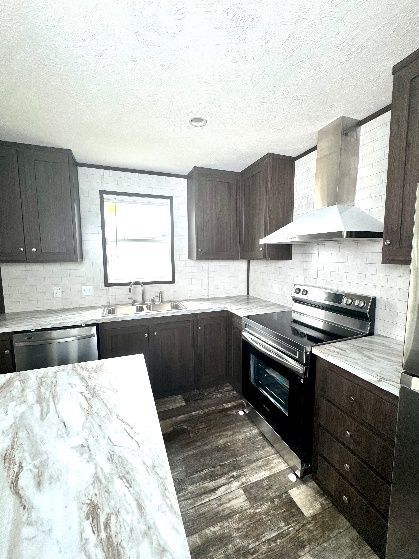 Kitchen with dark brown cabinets, white countertops, and stainless steel appliances. The floor is a light brown wood-look vinyl.