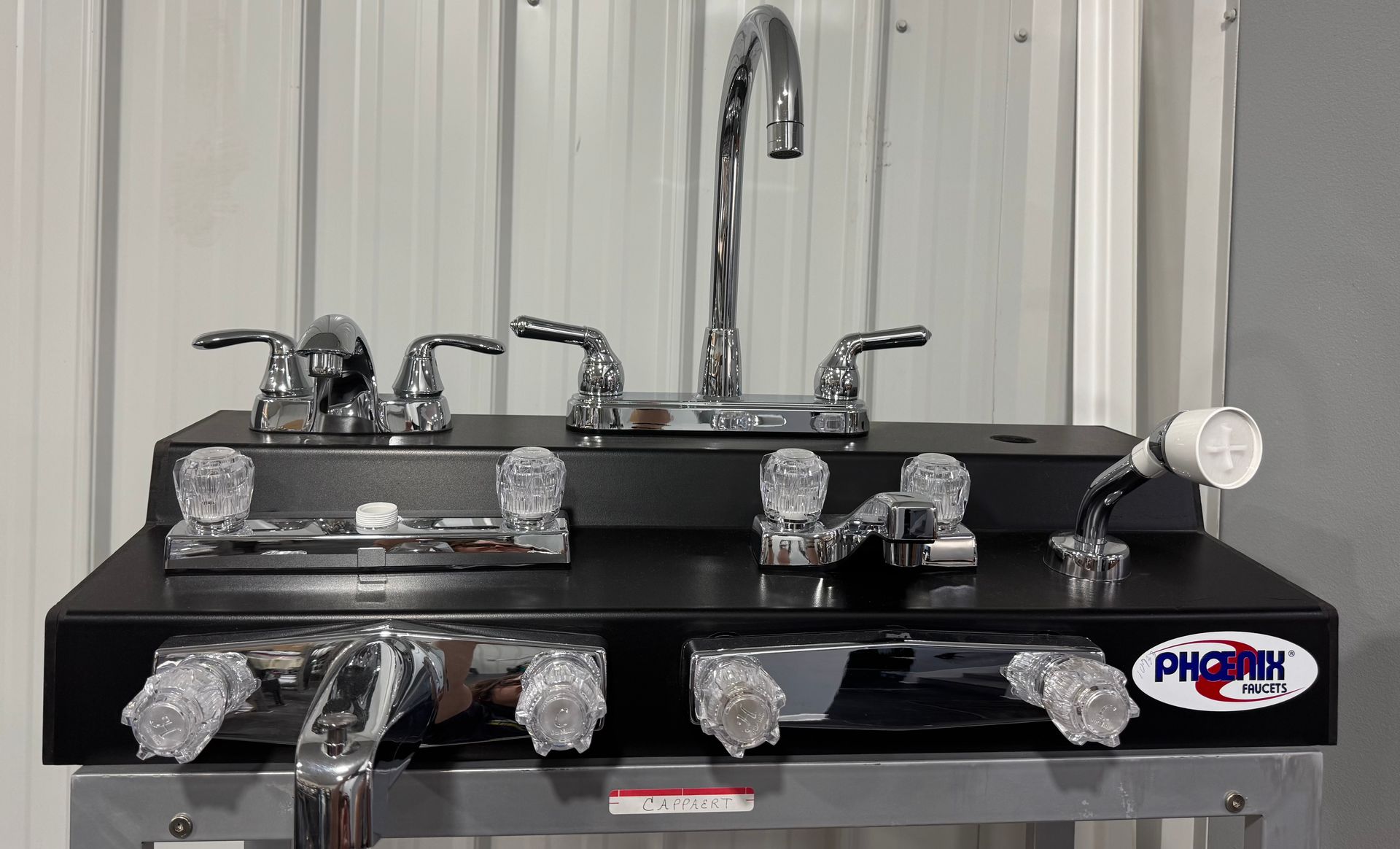 A black counter top with chrome faucets and knobs on it