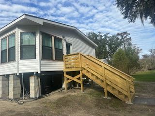 A mobile home with a wooden deck and stairs.